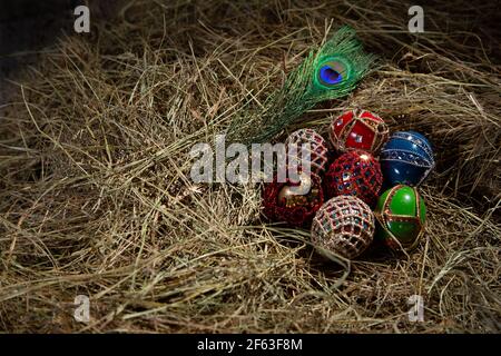 EASTER EGGS DECORATED  AS FABERGE EGGS IN A STRAW NEST WITH PEACOCK FEATHER Stock Photo