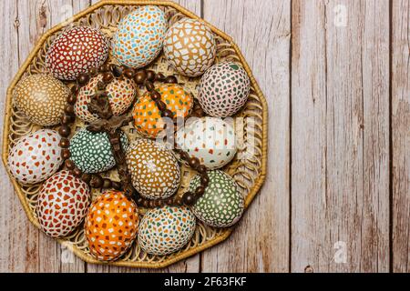 Happy Easter.Colorful hand made Easter eggs with crucifix in wooden basket copy space for text.Spring decoration background. Festive tradition Stock Photo