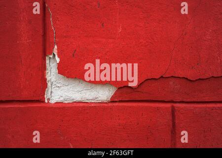 red background, crack in the cement. A bright red concrete wall with a large crack in the plaster. Beautiful textured background. Stock Photo