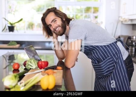 Portrait of caucasian man in kitchen wearing apron and using tablet Stock Photo