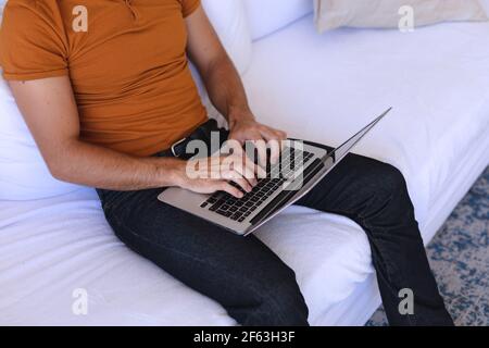 Caucasian man sitting on sofa using laptop Stock Photo