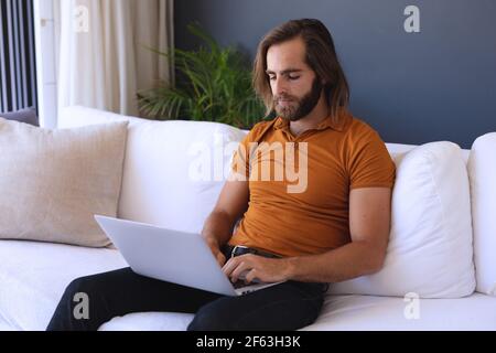 Caucasian man sitting on sofa using laptop Stock Photo