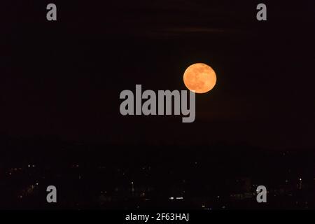 UK Moonrise, Wembley Park, UK. 29th March 2021.Stunning Waning Gibbous Moon rising a deep orange red. Amanda Rose/Alamy Live News