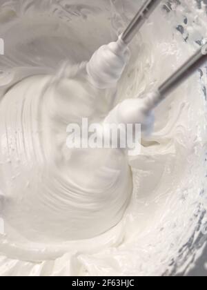 Beating a white cream with a mixer in a metal bowl. Whipped cream. Cream  for the cake Stock Photo - Alamy