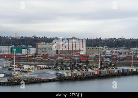 Buildings on the waterfront of the port of Seattle with headquarter of Starbucks situated near container terminal with containers and forklifts. Stock Photo