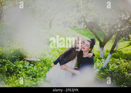 Happy mother's day. Little girl hugs her mother in the spring cherry garden. Portrait of happy mother and daughter among white flowers trees. Family v Stock Photo