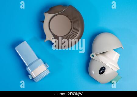 Different types of COPD or Asthma medication instruments ,discus and handihaler and a capsule inhaler.On blue background. Stock Photo