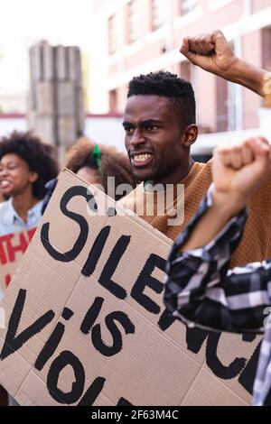 African american man with protesters on march holding signs and raising fists Stock Photo