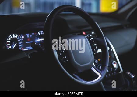 black leather multi-function steering wheel in the interior of a premium SUV. car dashboard. control buttons. matte toned Stock Photo