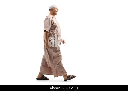 Full length profile shot of a mature muslim man in traditional clothes walking isolated on white background Stock Photo