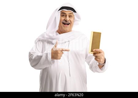 Happy mature arab man holding a gold bar and pointing isolated on white background Stock Photo