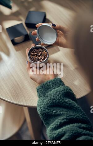 Female hand holds bowl of ground coffee and beans in gift box on the table Stock Photo