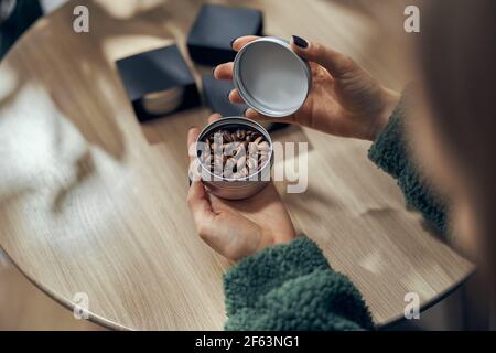 Female hand holds bowl of ground coffee and beans in gift box on the table Stock Photo