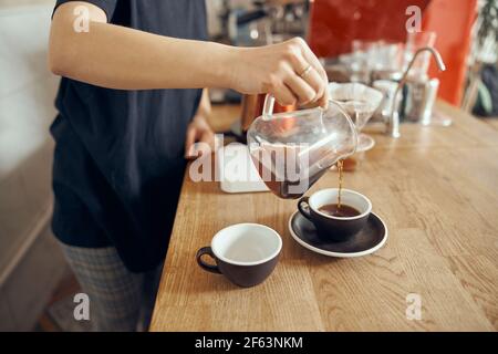 Professional barista photo of barista at counter in cafe pouring filter coffee in cup. Alternative ways of brewing coffee. Coffee shop concept Stock Photo