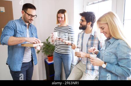 Group of young cheerful happy coworkers having a break together with coffee in the paper cup. Stock Photo