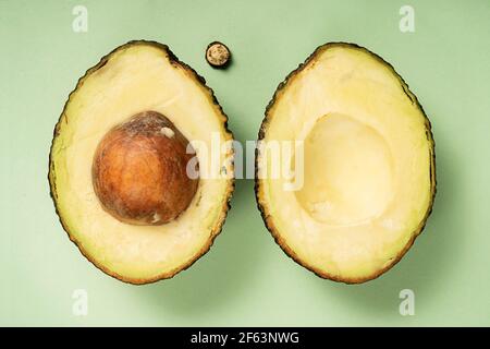 Avocado Hass cut in half. Top view. Healthy food. Fruit on a green background. Stock Photo