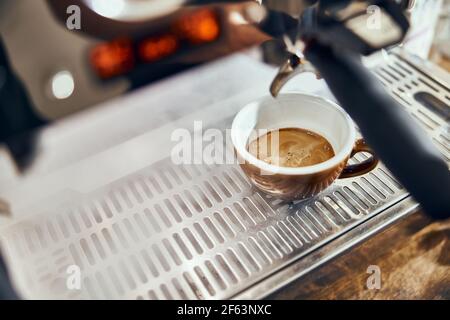 Close-up of espresso pouring from coffee machine. Professional coffee brewing. Stock Photo