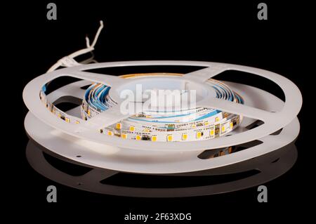 Flexible light emitting diode LED strip in the reel isolated on the black reflective background Stock Photo