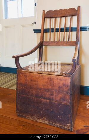 Antique wooden armchair toilet in living room inside an old 1825 Canadiana cottage style fieldstone home Stock Photo