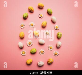 Colorful Easter eggs and flowers form a egg on purple background. Spring holidays concept Stock Photo