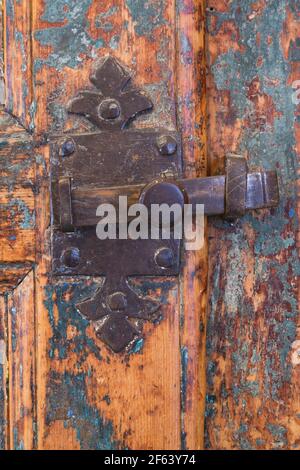 Close-up of rusted metal latch with Fleur-de-Lys design on old distressed door from 1864 in family room inside old 1825 Canadiana cottage style home Stock Photo
