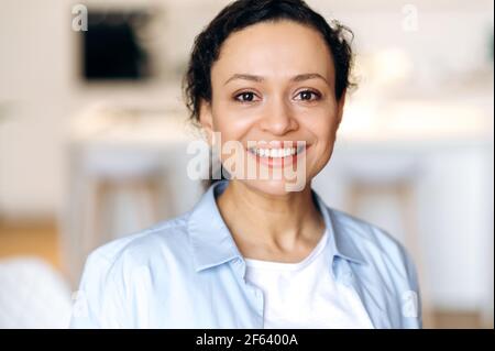 Close-up portrait of beautiful joyful successful mature mixed race brunette woman, dressed in stylish shirt, employee or lawyer, looking at camera, smiling friendly Stock Photo
