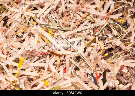 Close-up of pair of steel scissors on top of shredded paper pile Stock Photo