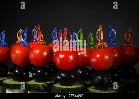 Many beautiful canapes on skewers on a gray background Stock Photo