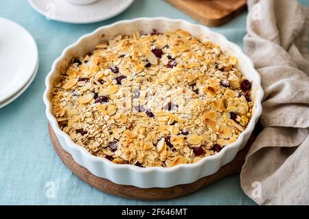 Whole apple pear crumble with ice cream, streusel. Sweet dessert with stewed fruit topped crisp crumbly mixture served ice cream. Apple cobbler pie in baking dish on tablecloth. Side view Stock Photo