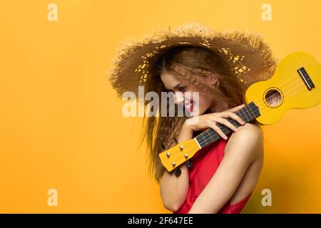 Woman holding Ukulele straw hat lifestyle Exotic yellow background Stock Photo