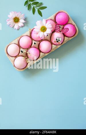 Minimal Easter concept. Festive spring mood, natural decor. Easter eggs in pink tones and gerbera flower on pastel blue background. Top view flat lay. Stock Photo