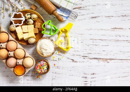 Baking or cooking background frame. Ingredients, kitchen items for Easter festive baking. Kitchen utensils, flour, brown sugar, eggs, butter, confetti Stock Photo