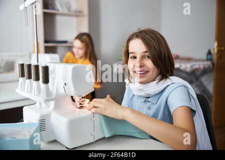 Cheerful girl using sewing machine in tailor studio Stock Photo