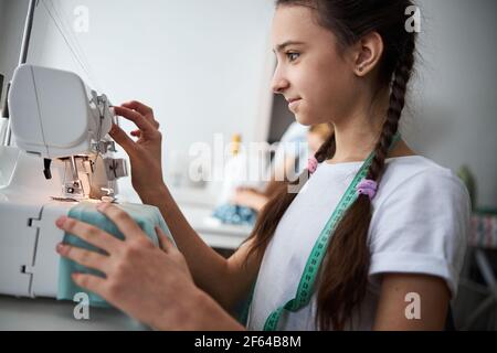 Adorable girl using modern sewing machine in workshop Stock Photo