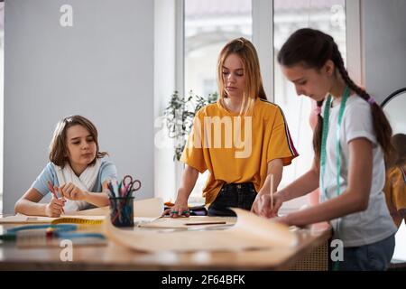 Cute female children drafting sewing patterns in workshop Stock Photo