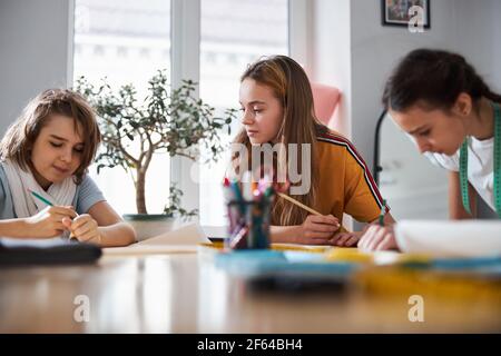 Adorable female kids drafting sewing patterns in workshop Stock Photo