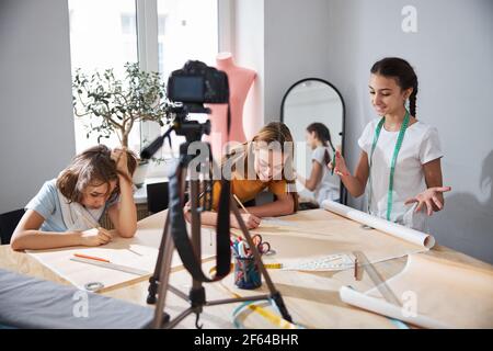 Adorable girls recording video for sewing blog in workshop Stock Photo