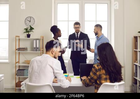 Multiethnic group of employees and team leader working in busy open space office Stock Photo