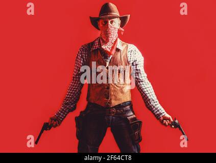 Cowboy with weapon on red background. American bandit in mask, western man with hat. Farmer or cowboy in hat. Man wearing cowboy hat, gun. West, guns Stock Photo