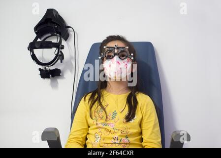 Little girl doing eye test at optometrist. Children caring for eye concept Stock Photo