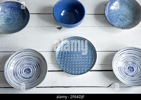 Empty ceramic tableware. Ceramic plates on wooden surface. Overview empty food table with tableware. Set of different modern blue plates. Stock Photo