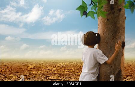 Girl hugging a tree on the cracked earth background. Global warming. Stock Photo
