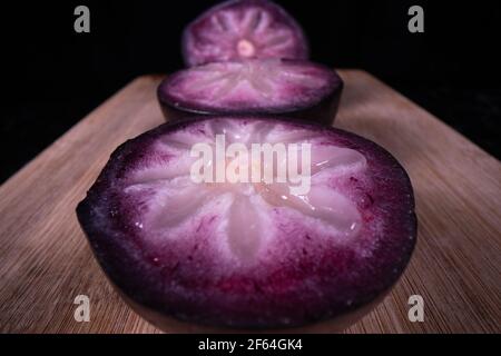 A ripe star apple showing the colourful fruit cut in half, a popular seasonal fruit in the Philippines. Stock Photo