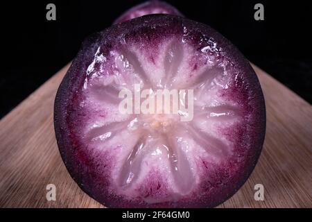 A ripe star apple showing the colourful fruit cut in half, a popular seasonal fruit in the Philippines. Stock Photo