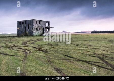 Vehicle tyre marks in the grass left by joy riders in front of the derelict control tower on the disused WW2 RAF Davidstow Airfield on Bodmin Moor in Stock Photo