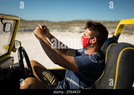 Caucasian man wearing face mask sitting in beach buggy taking picture Stock Photo