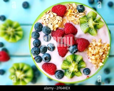 Healthy breakfast - the bowl of oat granola with yogurt, fresh raspberries, blueberries, kiwi and nuts Stock Photo