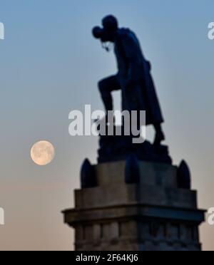 Brighton UK 30th March 2021 - The Worm Moon can still be seen early in the morning at Brighton on what is forecast to be the warmest day of the year so far with temperatures expected to reach the mid 20s in some parts of the UK :  Credit Simon Dack / Alamy Live News Stock Photo