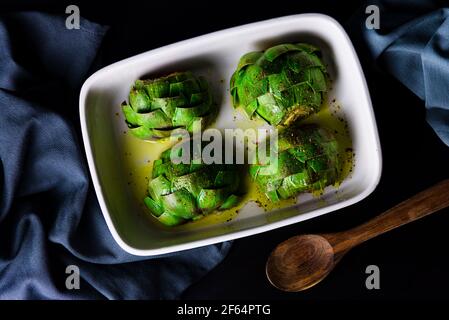 Oven roasted artichokes with olive oil, salt and pepper on a white tray Stock Photo