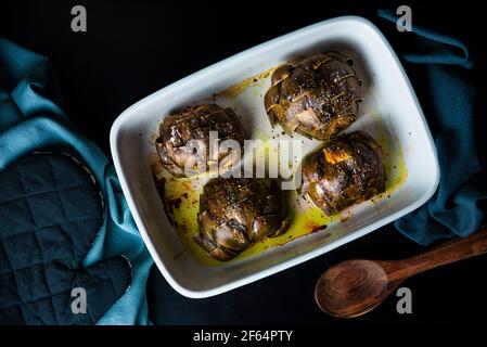 Oven roasted artichokes with olive oil, salt and pepper on a white tray Stock Photo